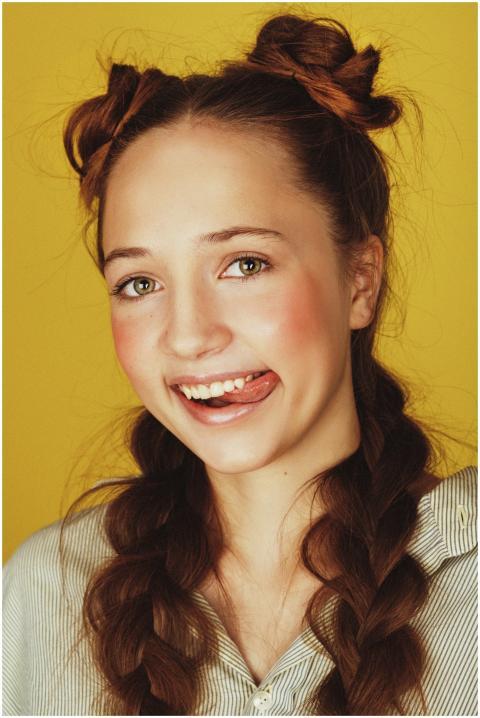 Cheerful young woman with braided hair smiling aga