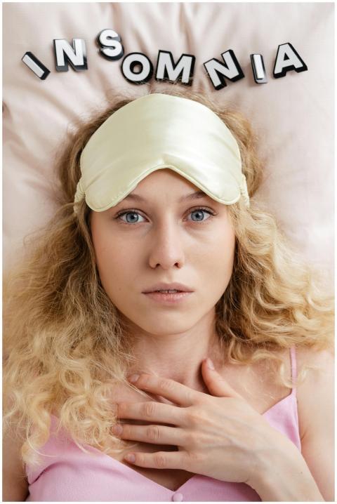 Blonde woman wearing a sleep mask, looking awake a