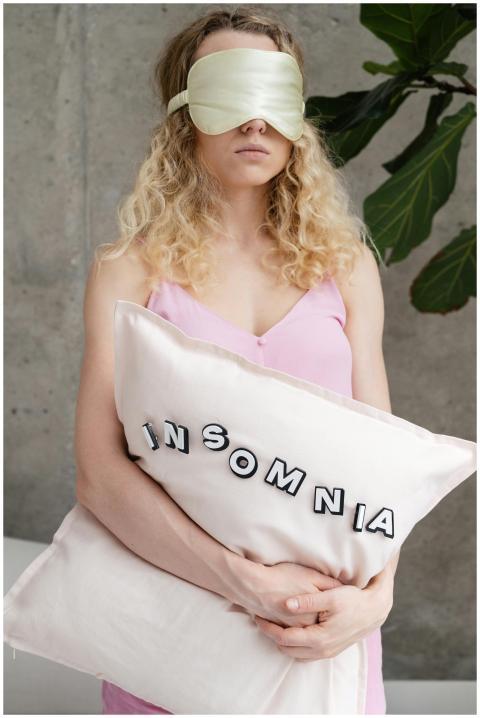Woman with sleep mask and insomnia pillow symboliz