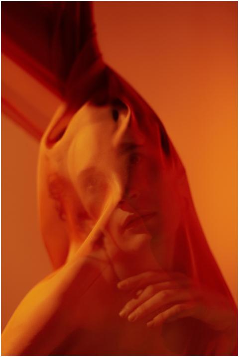 Artistic portrait of a person behind a red translu