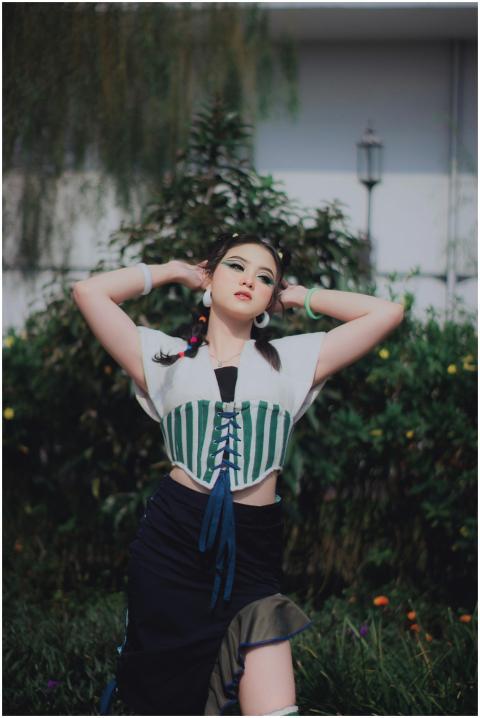 Young woman in fashionable attire poses in a lush