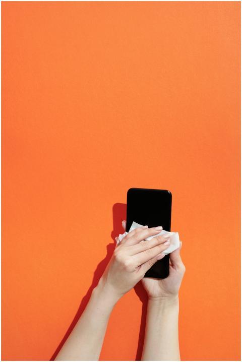 Close-up of hands sanitizing a smartphone against