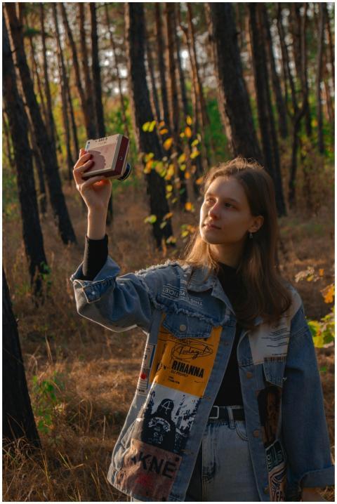 A young woman captures moments in a sunlit forest