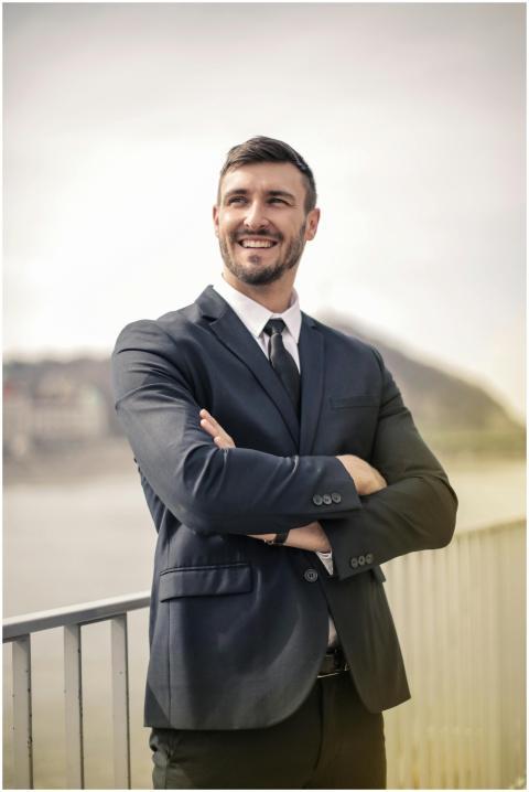 Smiling businessman in a black suit standing outdo
