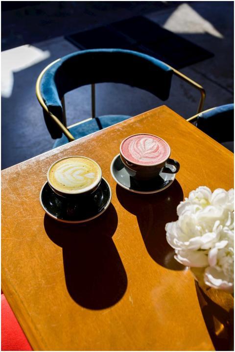 Two lattes with froth art on a café table, styled