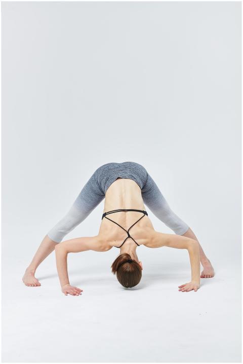 Woman practicing advanced yoga pose indoors showca