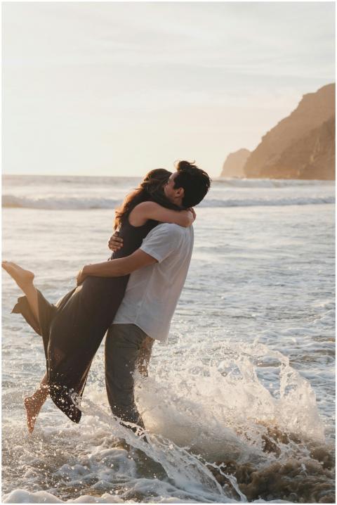 A couple embraces joyfully amid ocean waves during