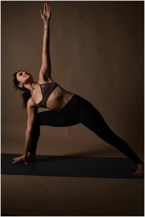 A woman performs a yoga pose on a mat with a neutr