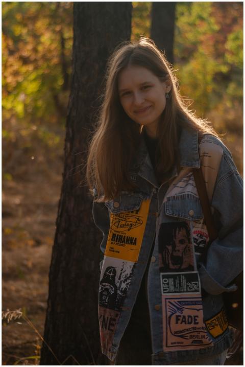Young woman smiling in a park wearing a denim jack