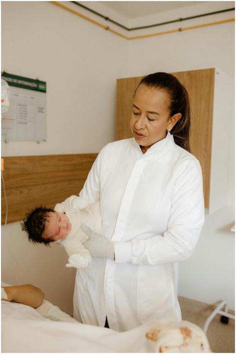 A female doctor gently holds a newborn baby in a h