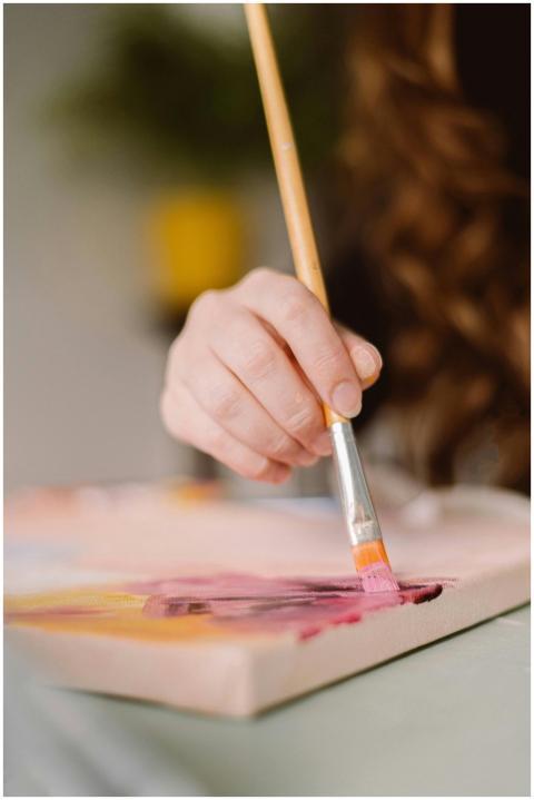 A close-up of a female artist's hand painting on a