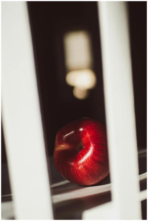 A vibrant red apple on a chair with dramatic light