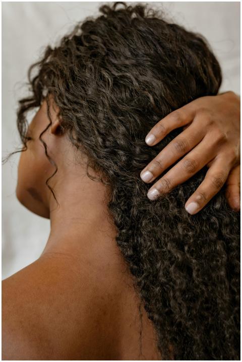 A close-up of a woman with curly hair viewed from