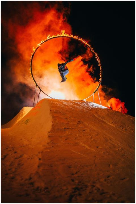 Daring snowboarder jumps through a flaming ring at