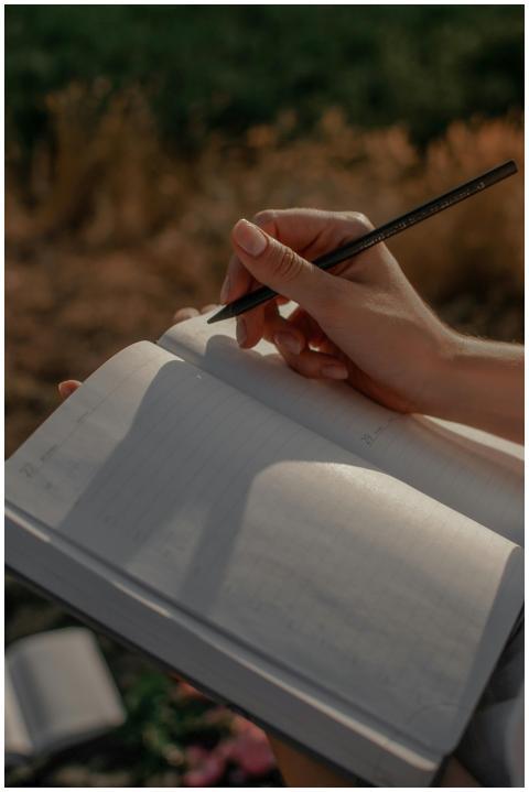 Close-up of a woman writing in a journal outdoors