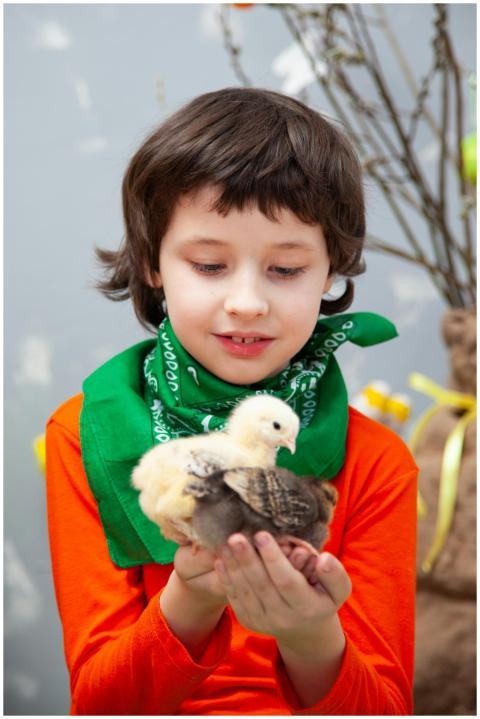Young boy wearing green scarf cuddles adorable chi