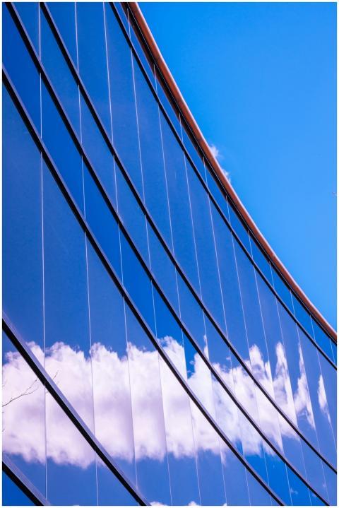 Contemporary glass facade reflecting bright blue s