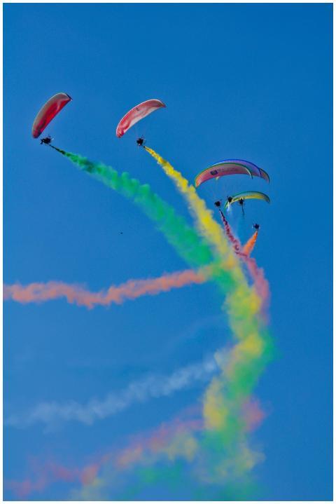 A group of paragliders create vibrant smoke patter