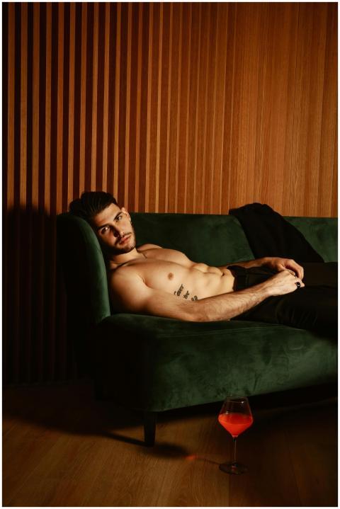 Muscular man with tattoos relaxes shirtless on a g