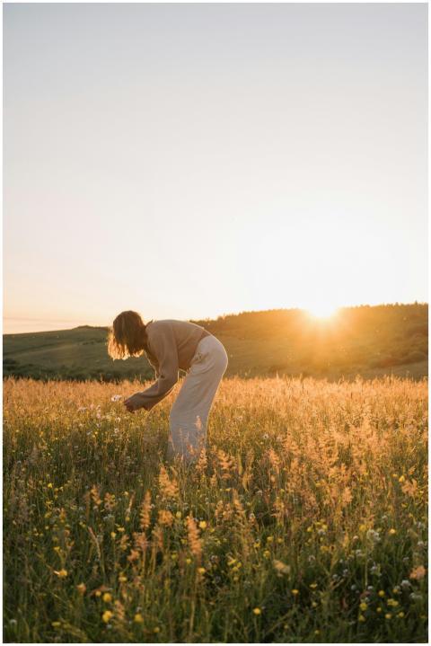 A woman picks wildflowers in a serene meadow durin