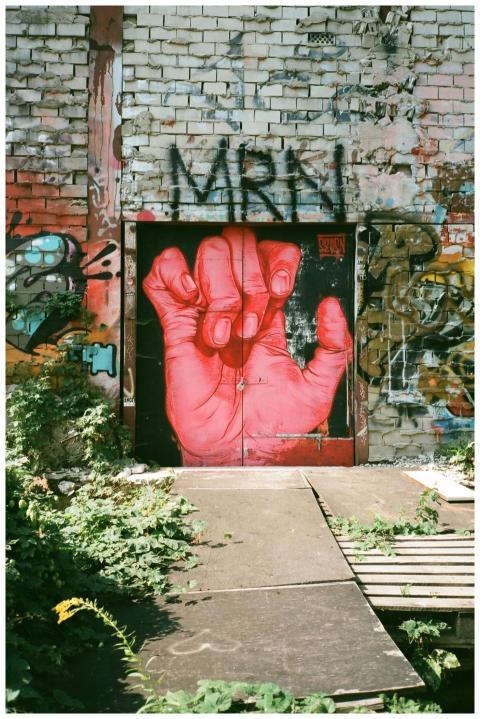 Colorful street art mural featuring a red hand on