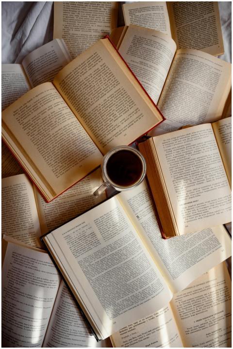 Top view of scattered open books with a cup of cof