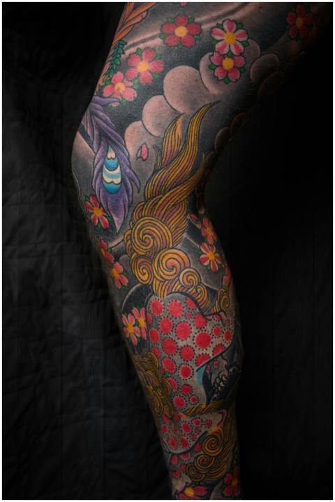 Vibrant floral tattoo covering a human leg with in