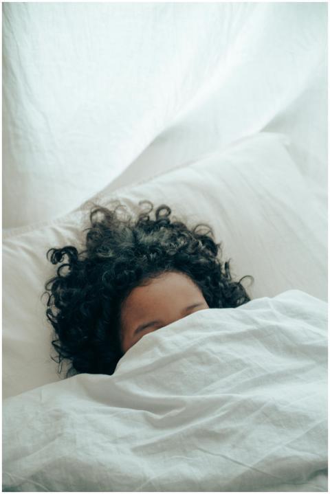 A person with curly hair sleeping peacefully under