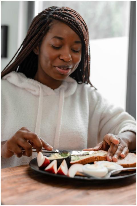 A woman spreads avocado on toast in a cozy kitchen