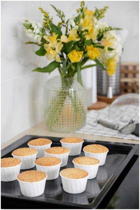 Tray of homemade cupcakes with a vase of yellow an