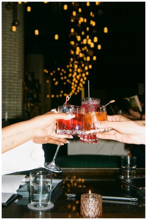 Friends raise colorful cocktails in a vibrant bar