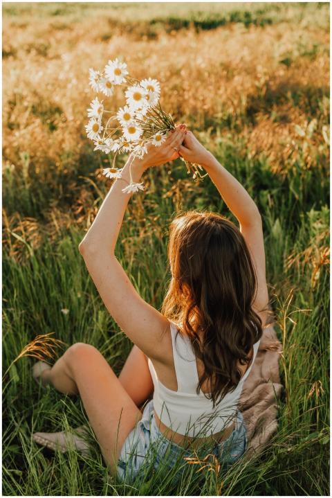 Young woman in a field holding daisies, capturing
