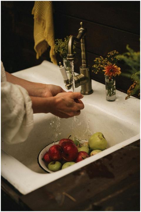 Hands washing apples in a vintage sink with rustic