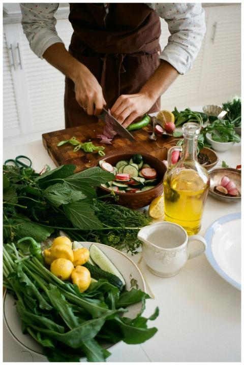 Adult preparing salad with fresh vegetables, knife