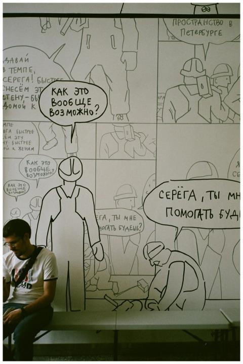 Illustrated comic wall with a man sitting and usin