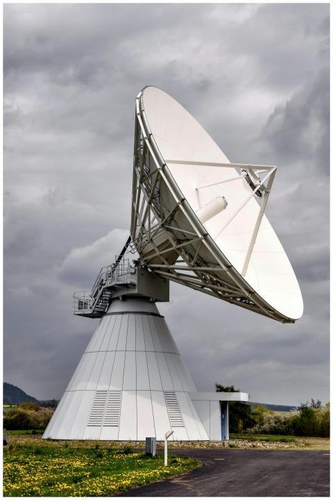 A large satellite dish in a rural area under a clo