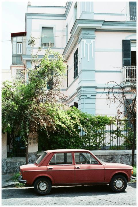 Retro Fiat 128 car parked by a classic Napoli buil