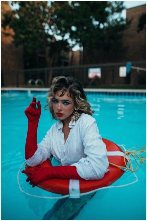 Fashionable woman poses in a swimming pool with a
