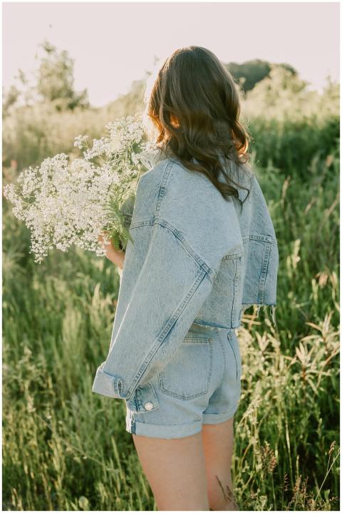 A woman in denim shorts and jacket holding a bouqu
