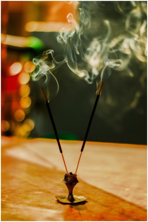 Artistic close-up of lit incense sticks with smoke