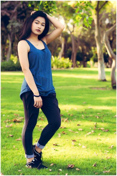 A stylish young woman stands confidently in a lush