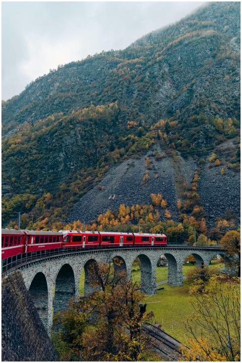 Red train traversing a scenic arch bridge in the S
