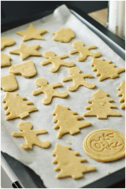 Raw festive holiday cookie dough shapes on parchme