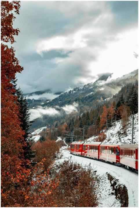 A vibrant red train travels through a snow-covered