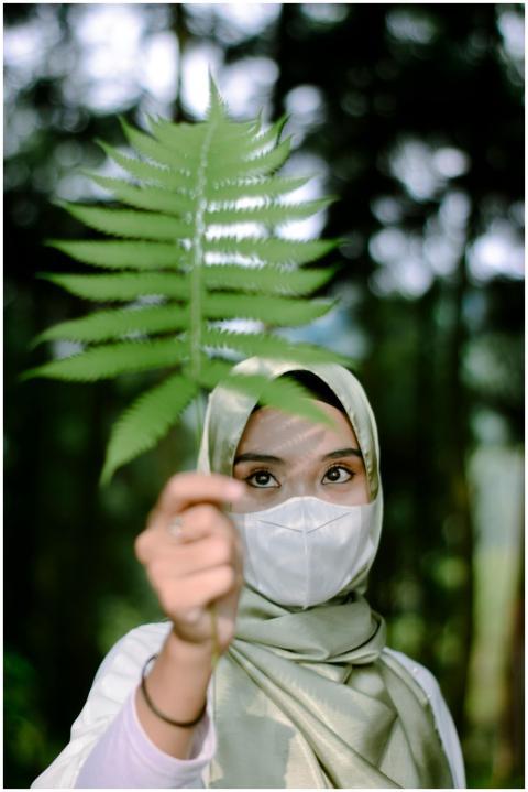 A young woman wearing a hijab and face mask holdin