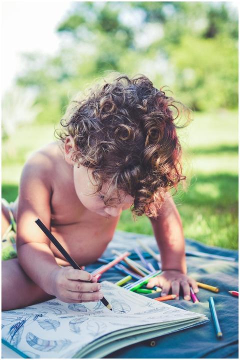 A young child drawing with colored pencils while s