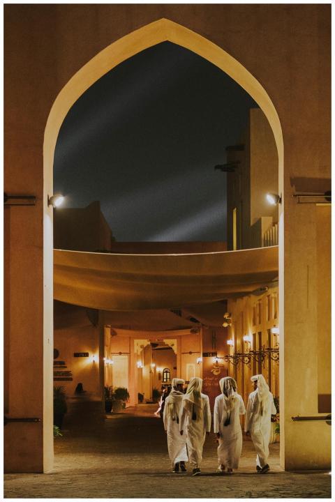 Men in traditional attire walking through illumina
