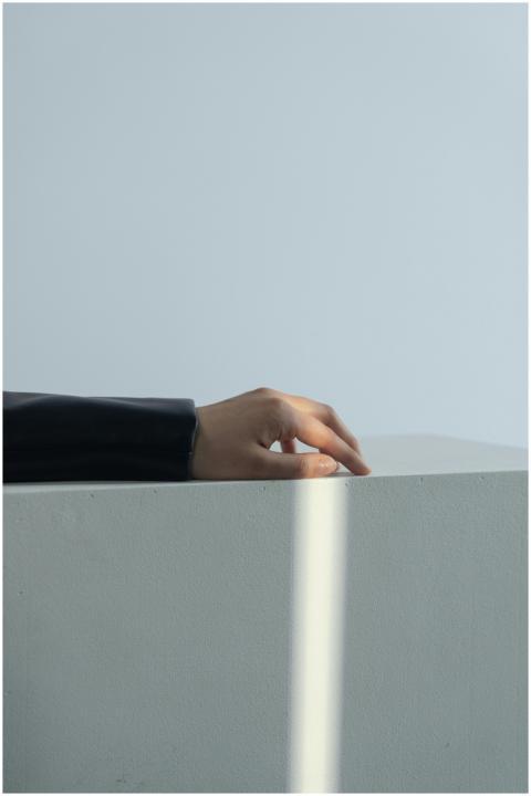 A hand in a black sleeve gently rests on a white s