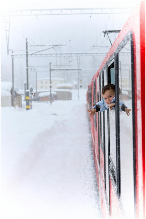 Boy enjoys snowy view from red train window in a w