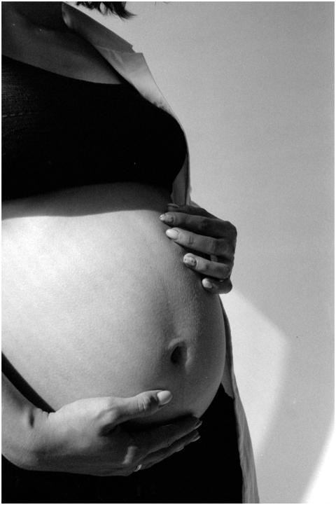 Black and white photo of a pregnant woman gently h
